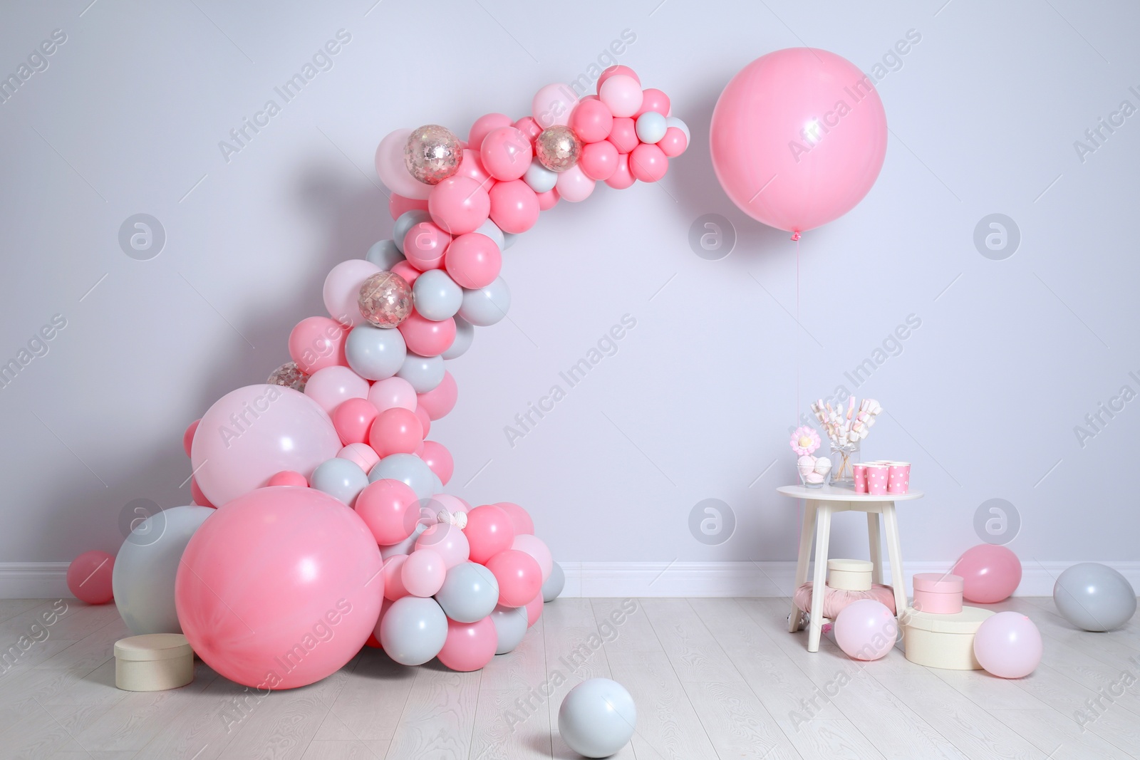 Photo of Beautiful composition with balloons and sweets near light wall