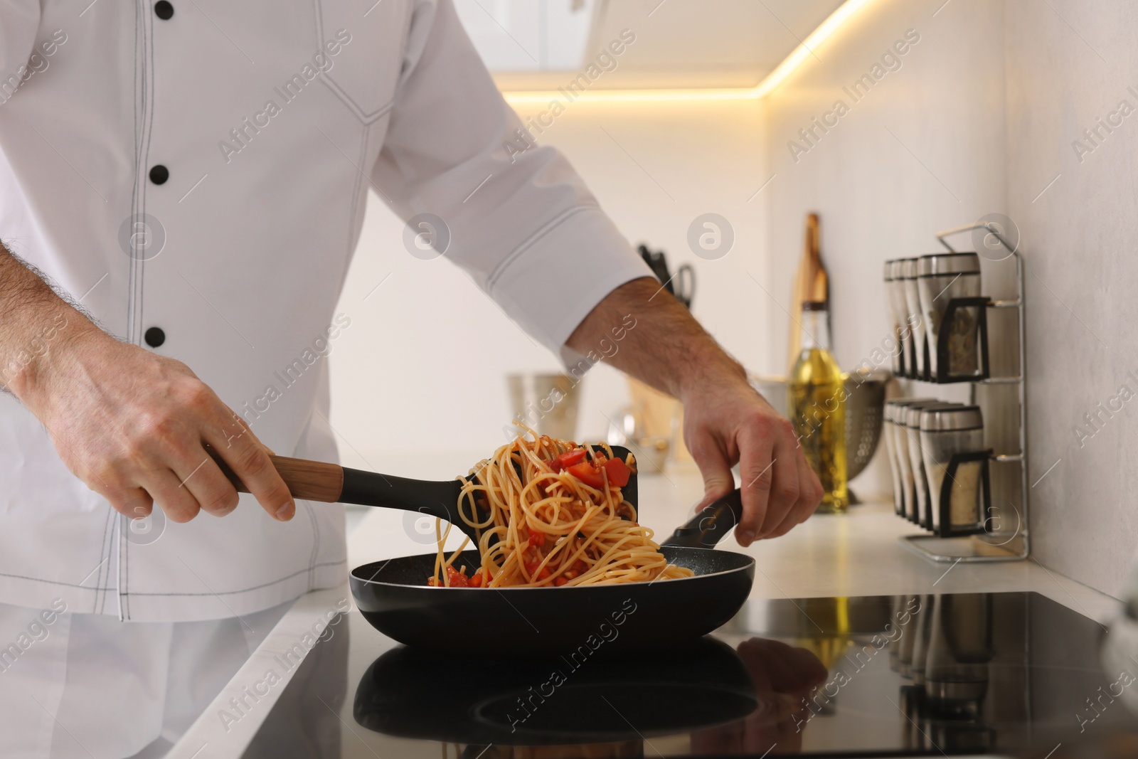 Photo of Professional chef cooking delicious pasta on stove in kitchen, closeup