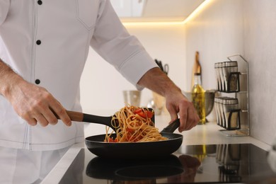 Professional chef cooking delicious pasta on stove in kitchen, closeup