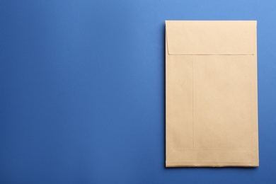 Kraft paper envelope on blue background, top view. Space for text