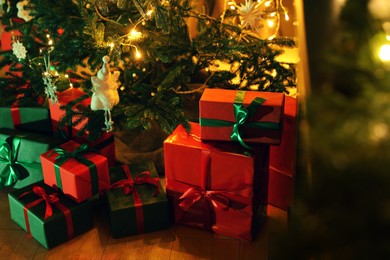 Photo of Beautifully wrapped gift boxes under Christmas tree indoors