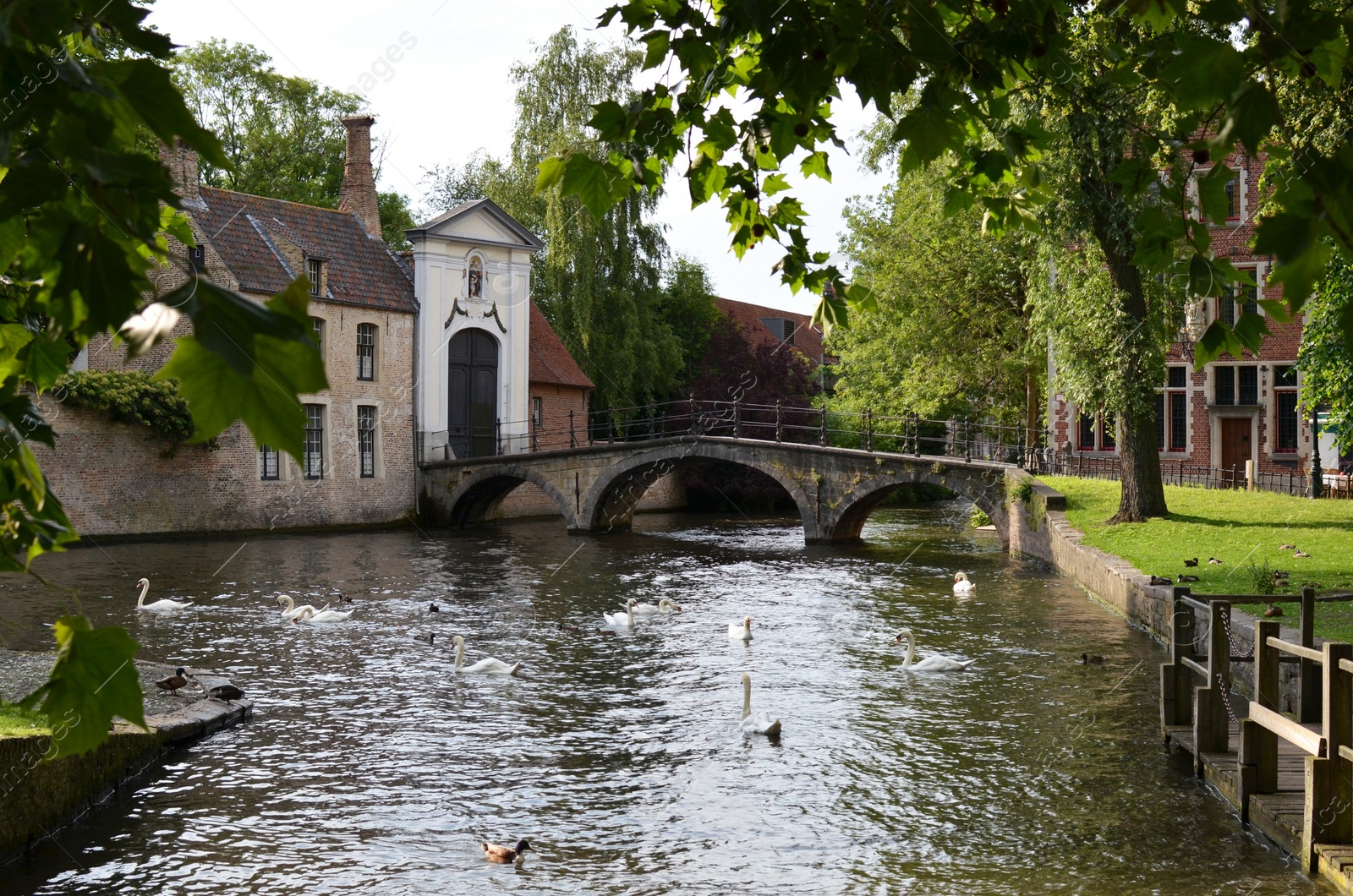 Photo of BRUGES, BELGIUM - JUNE 14, 2019: Bridge over canal and entrance gate to the Princely Beguinage Ten Wijngaerde