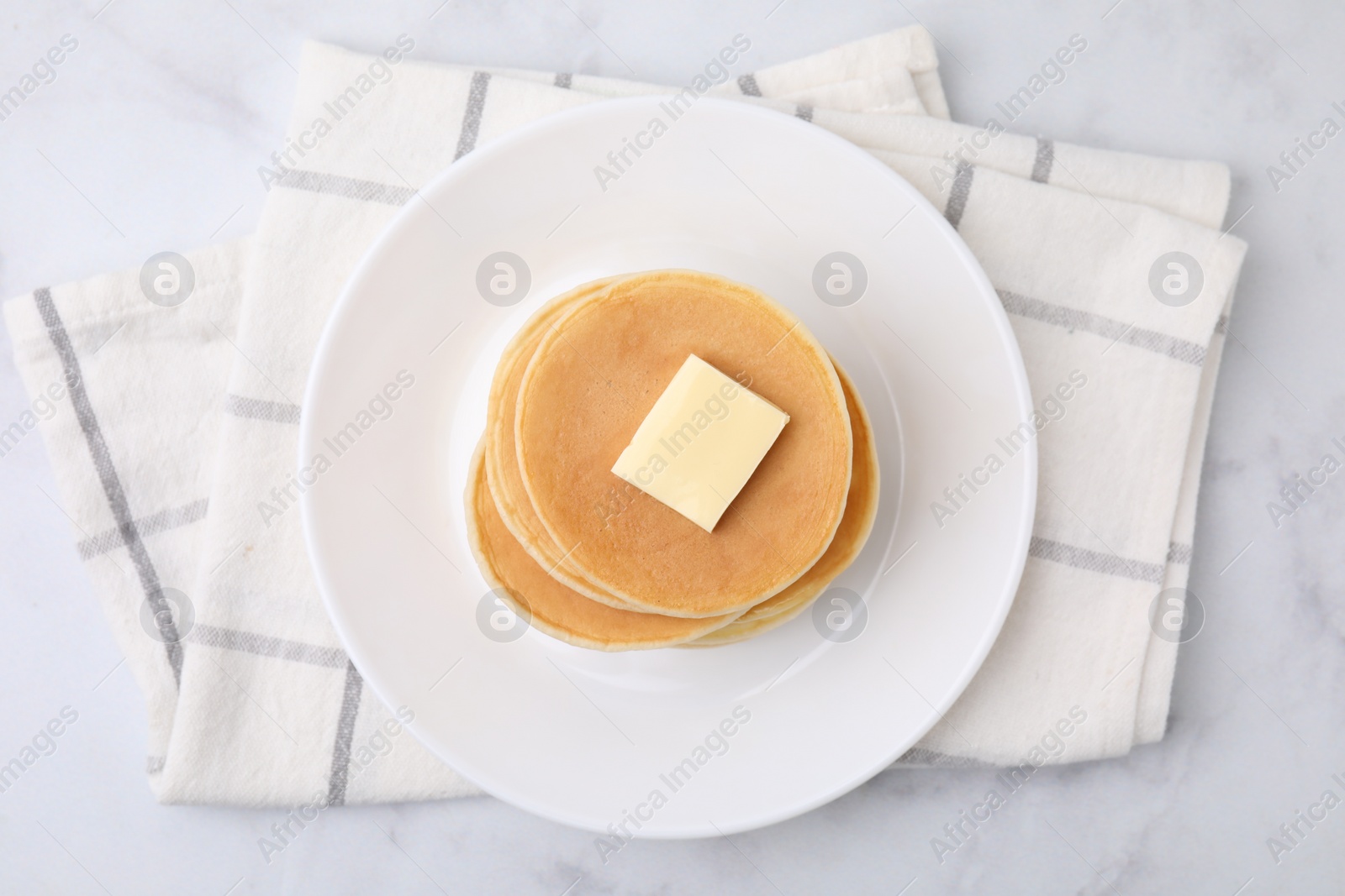 Photo of Delicious pancakes with butter on marble table, top view