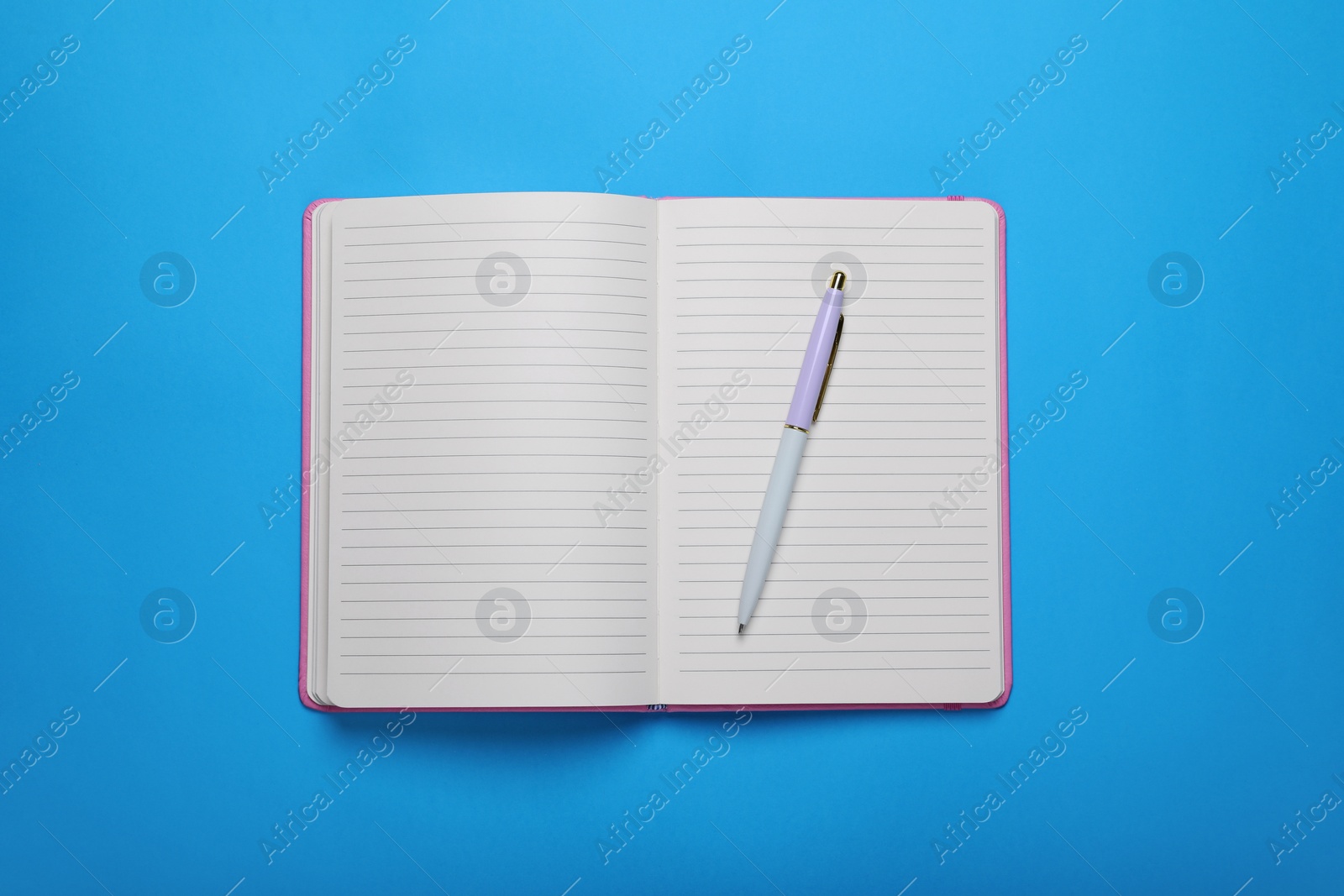 Photo of Open notebook and pen on light blue background, top view