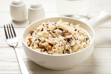 Photo of Delicious rice pilaf with mushrooms on white wooden table