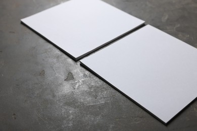 Photo of Blank paper sheets on grey textured table, closeup. Mockup for design