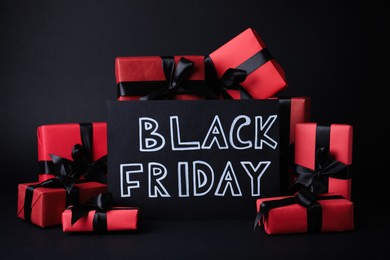 Gift boxes and card with words Black Friday on dark background