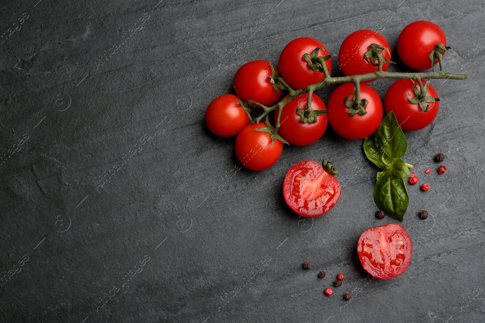 Photo of Fresh ripe cherry tomatoes, peppercorns and basil on black table, flat lay. Space for text