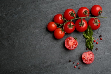 Fresh ripe cherry tomatoes, peppercorns and basil on black table, flat lay. Space for text