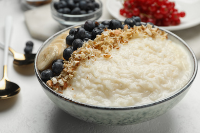 Photo of Delicious rice pudding with banana, blueberries and almond on light table, closeup