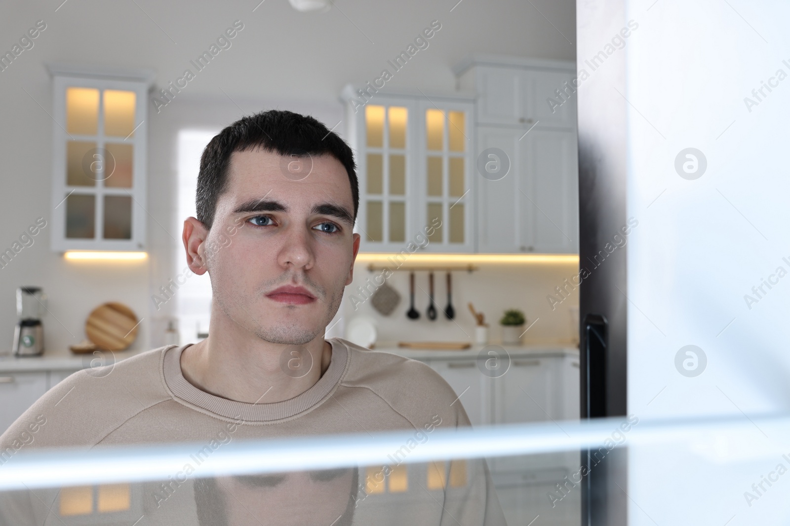 Photo of Upset man near empty refrigerator in kitchen, view from inside
