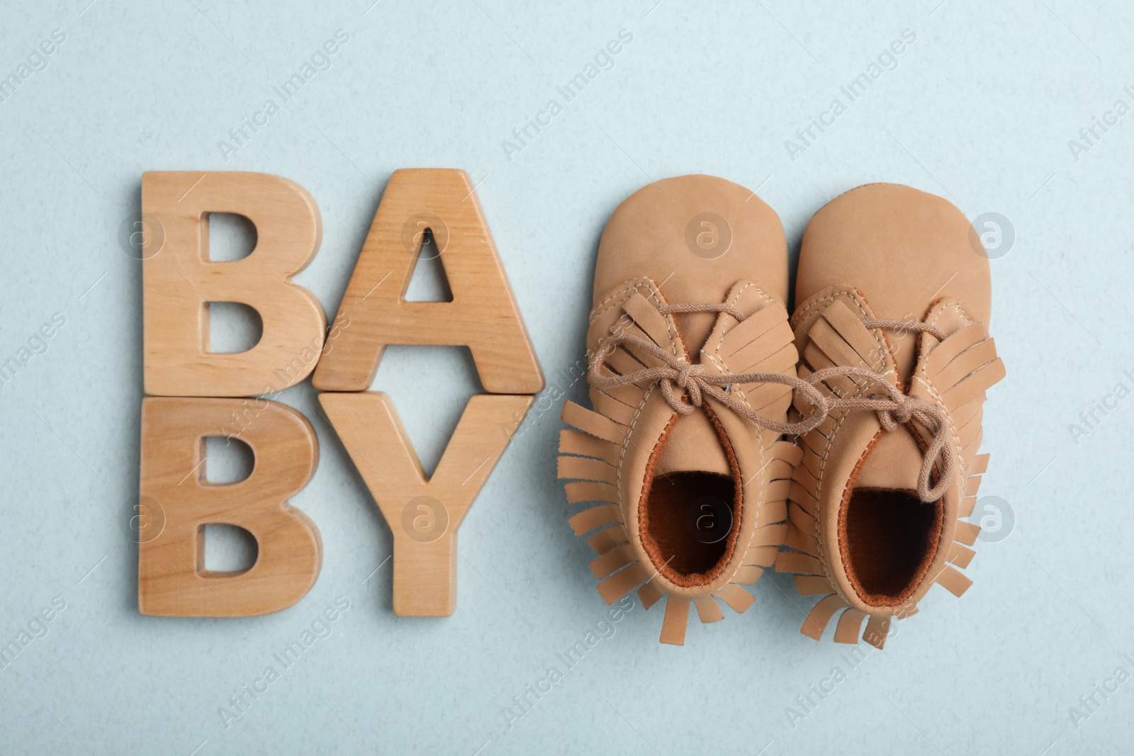 Photo of Flat lay composition with child's booties and word Baby on light background