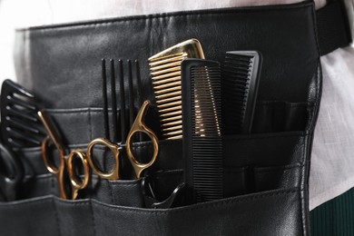 Photo of Hairstylist with professional tools in waist pouch, closeup