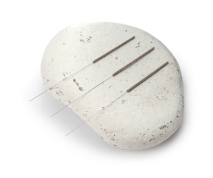 Needles for acupuncture and stone on white background