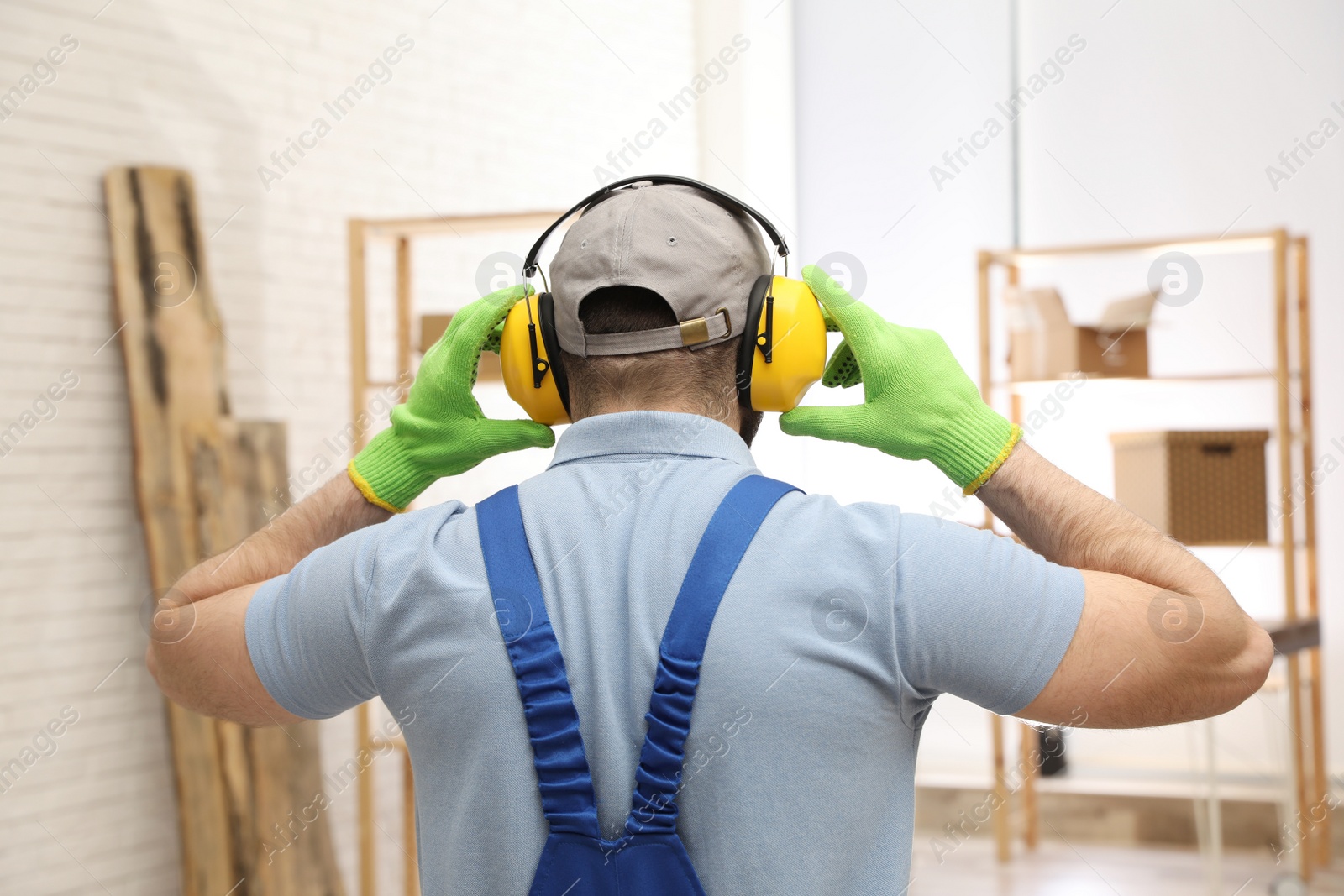 Photo of Worker wearing safety headphones indoors, back view. Hearing protection device