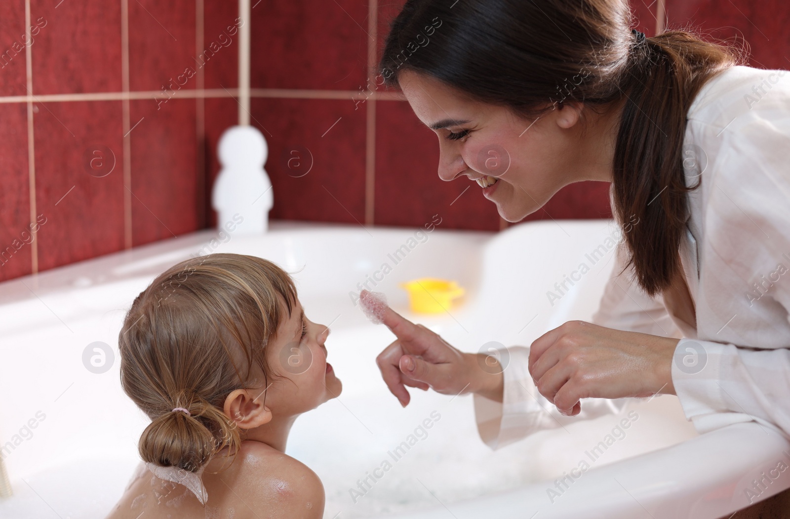 Photo of Happy mother with her little daughter spending time together in bathroom