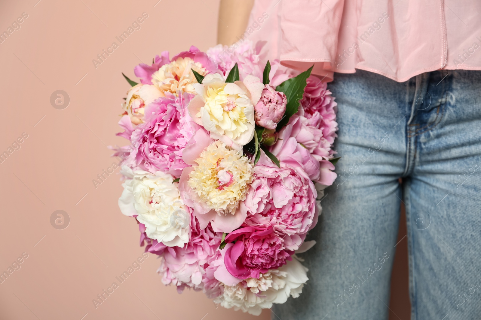 Photo of Woman with bouquet of beautiful peonies on beige background, closeup