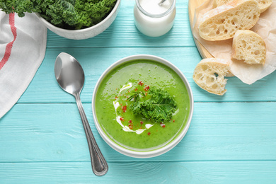 Photo of Tasty kale soup served on light blue wooden table, flat lay