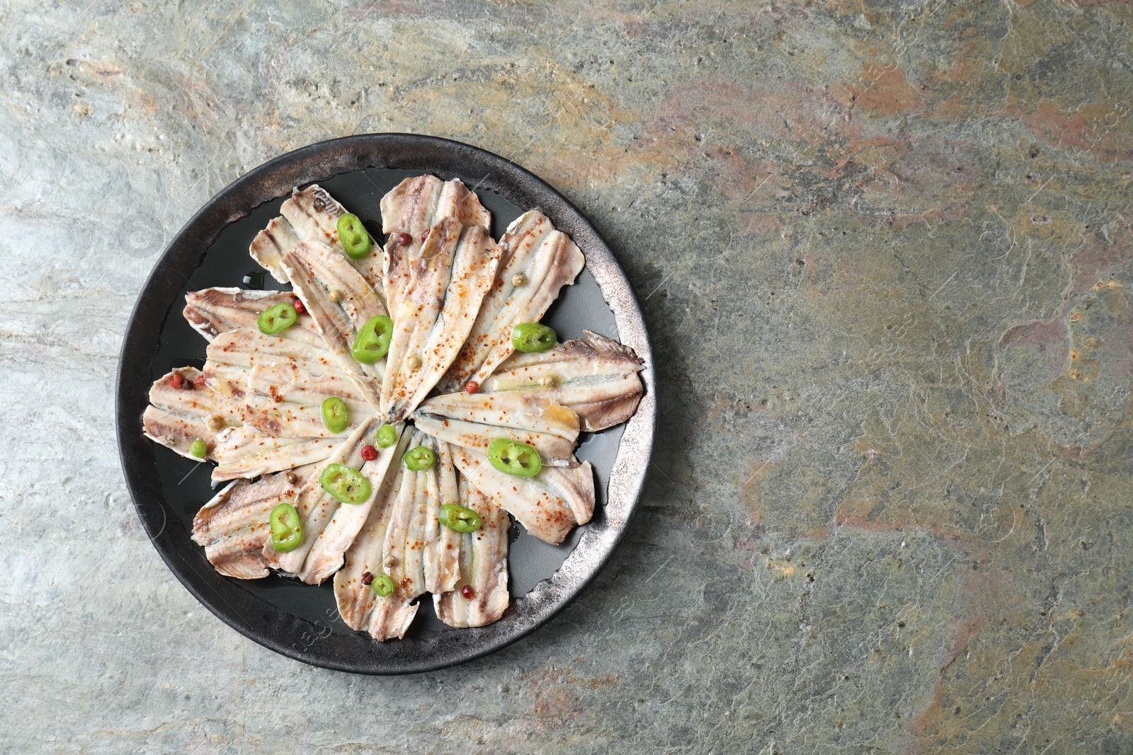 Photo of Tasty pickled anchovies with spices on textured table, top view. Space for text