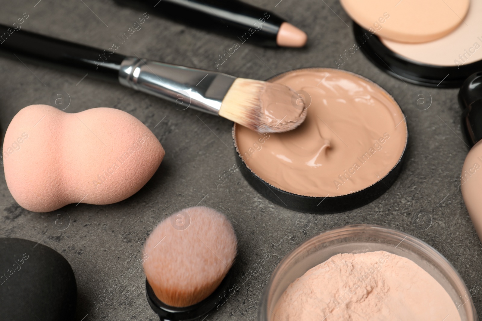 Photo of Composition with skin foundation, powder and beauty accessories on grey background