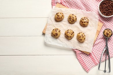 Photo of Uncooked chocolate chip cookies on white wooden table, flat lay. Space for text
