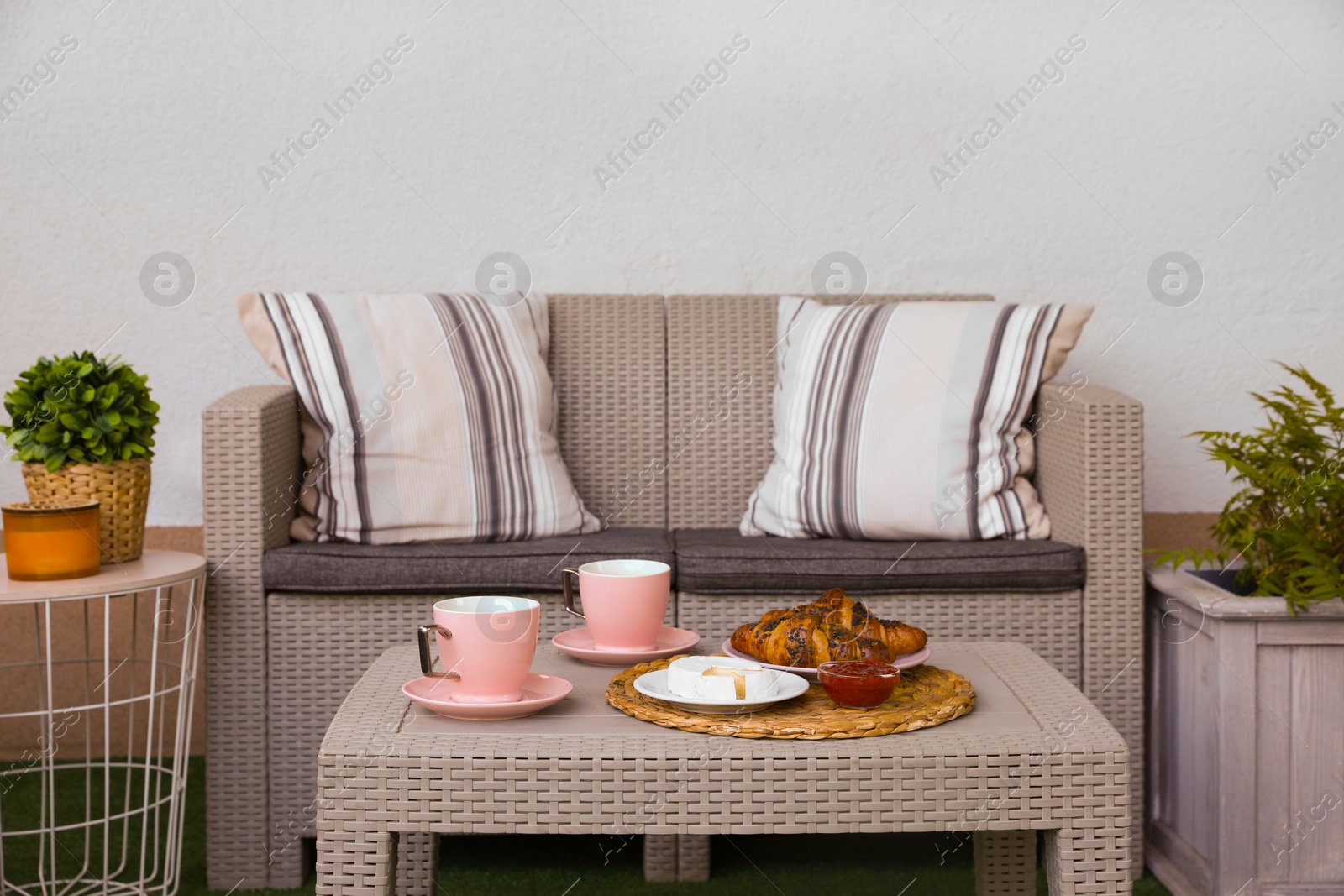 Outdoor breakfast with tea and croissants on rattan table on terrace Photo of Outdoor breakfast with tea and croissants on rattan table on terrace