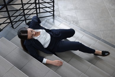Photo of Woman fallen down stairs suffering from pain in back, above view