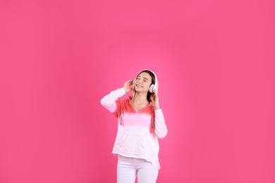 Photo of Teenage girl listening to music with headphones on color background