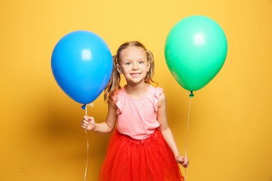 Cute girl with balloons on color background. Birthday celebration