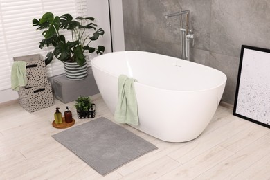 Stylish bathroom interior with soft bath mat and tub