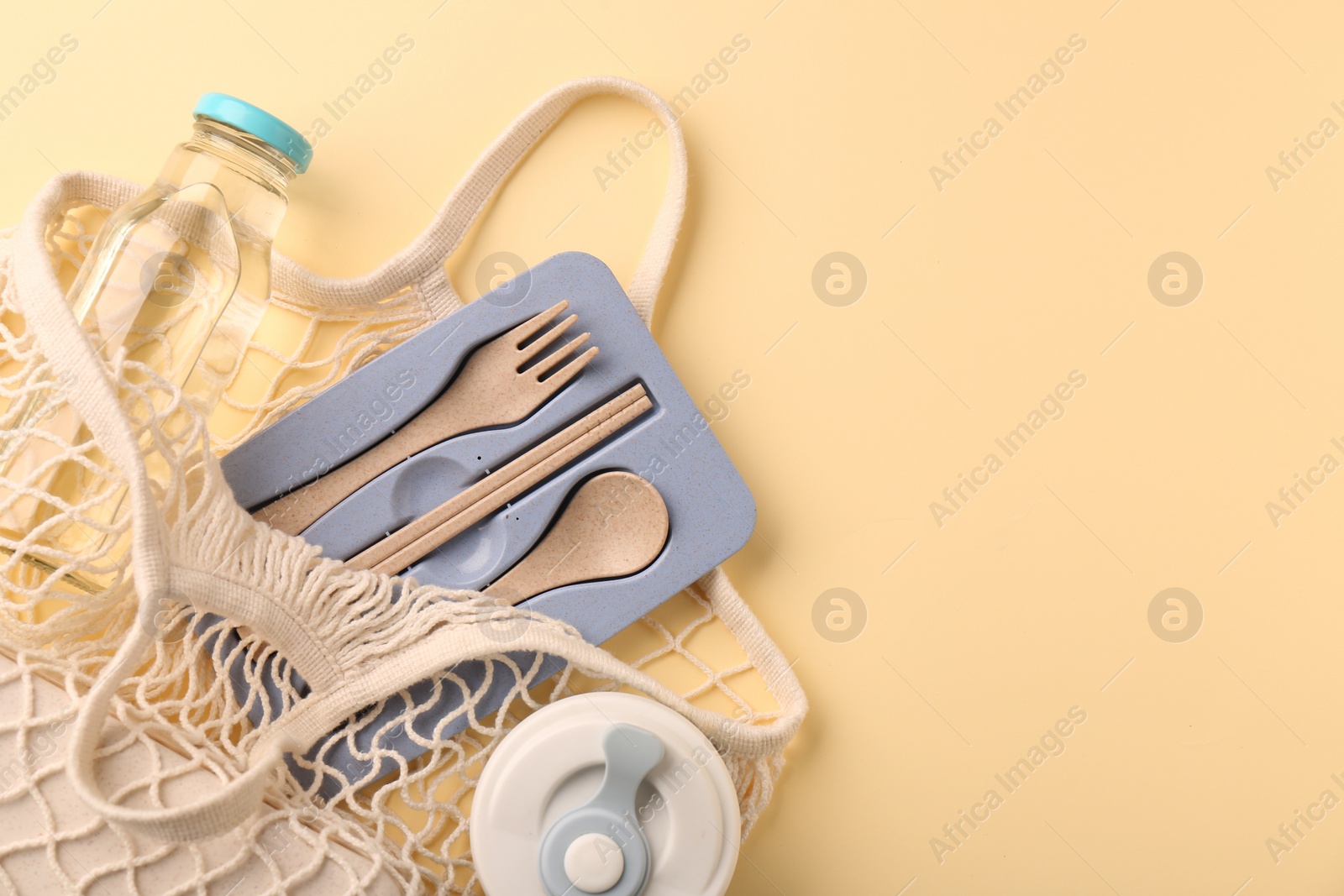 Photo of Fishnet bag with different items on beige background, top view and space for text. Conscious consumption