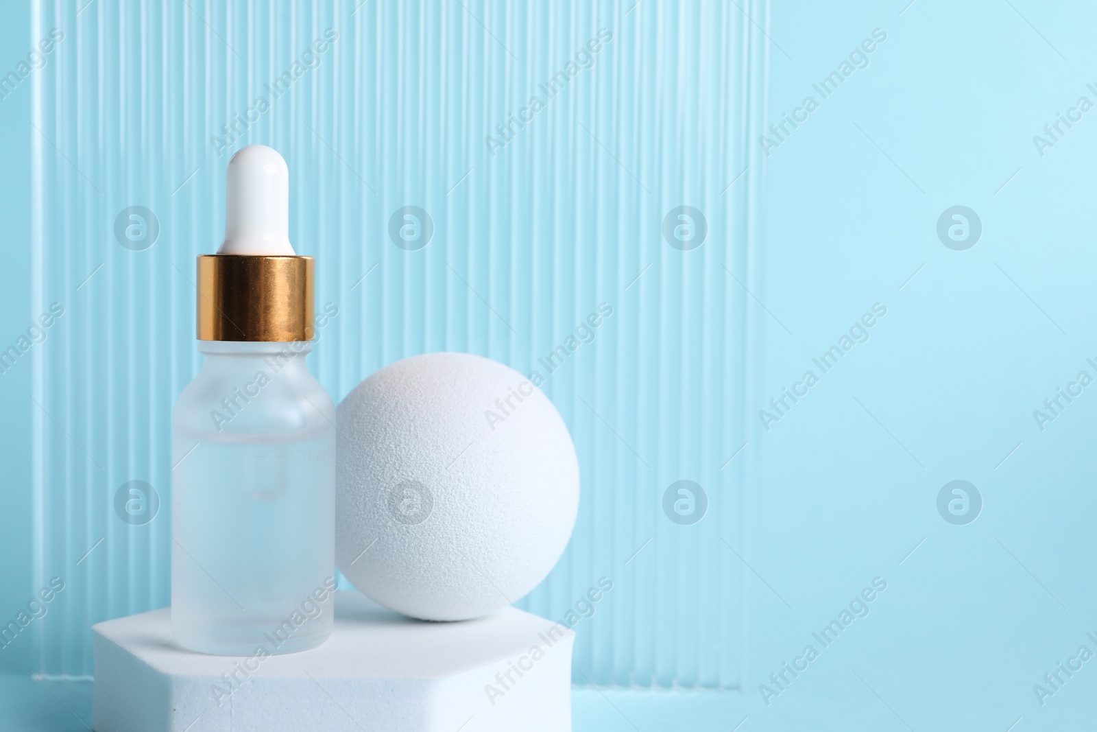 Photo of Stylish presentation of cosmetic serum on light blue background, space for text