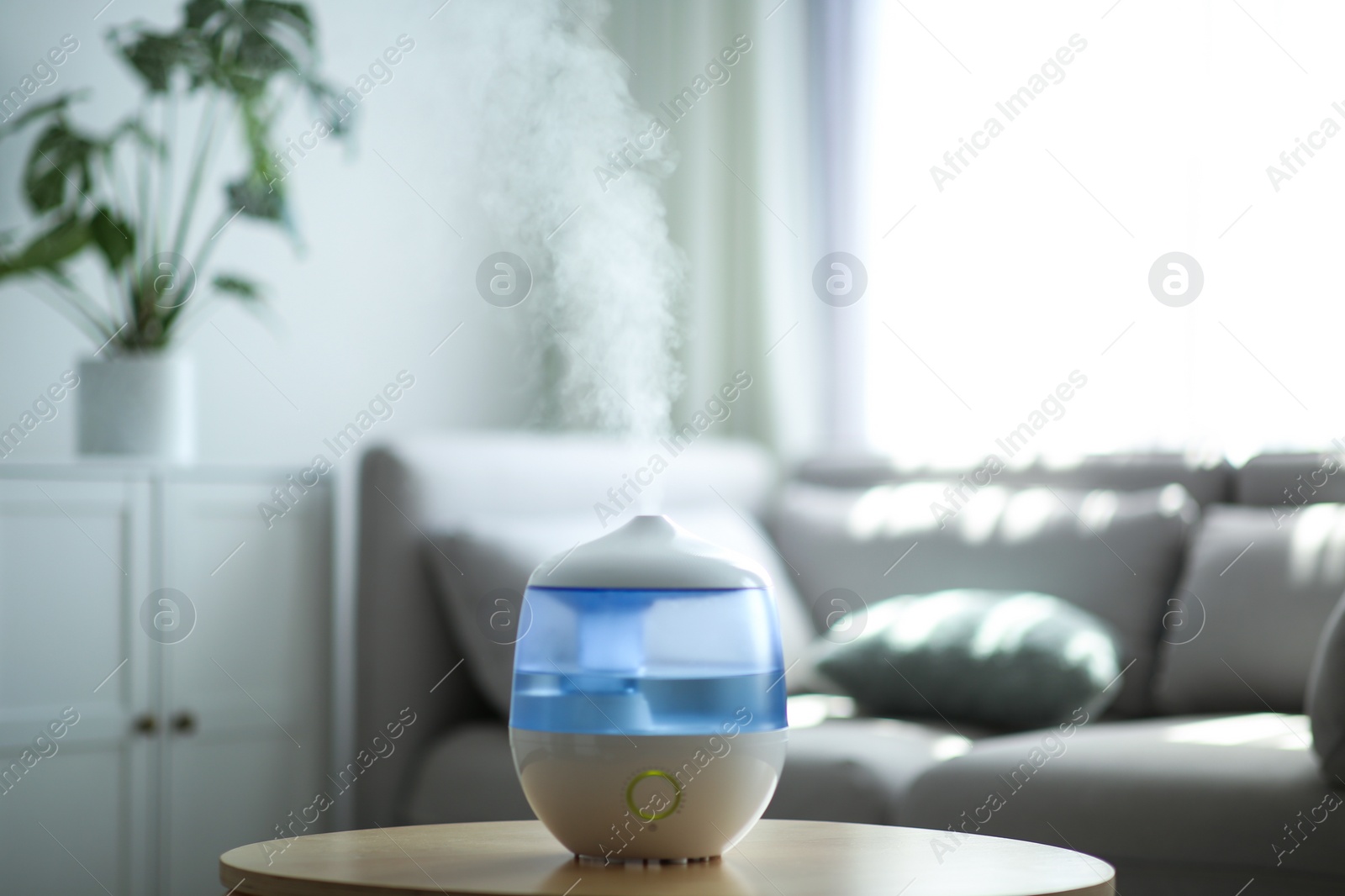 Photo of Modern air humidifier on table in living room