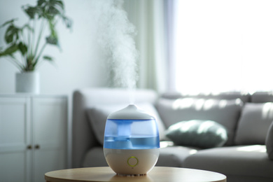 Photo of Modern air humidifier on table in living room