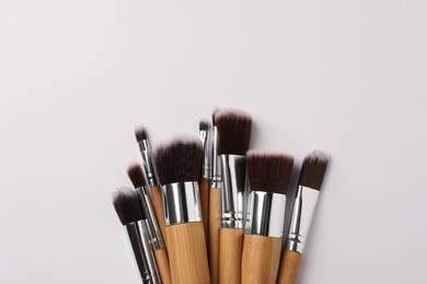 Photo of Set of makeup brushes on white background, flat lay. Space for text