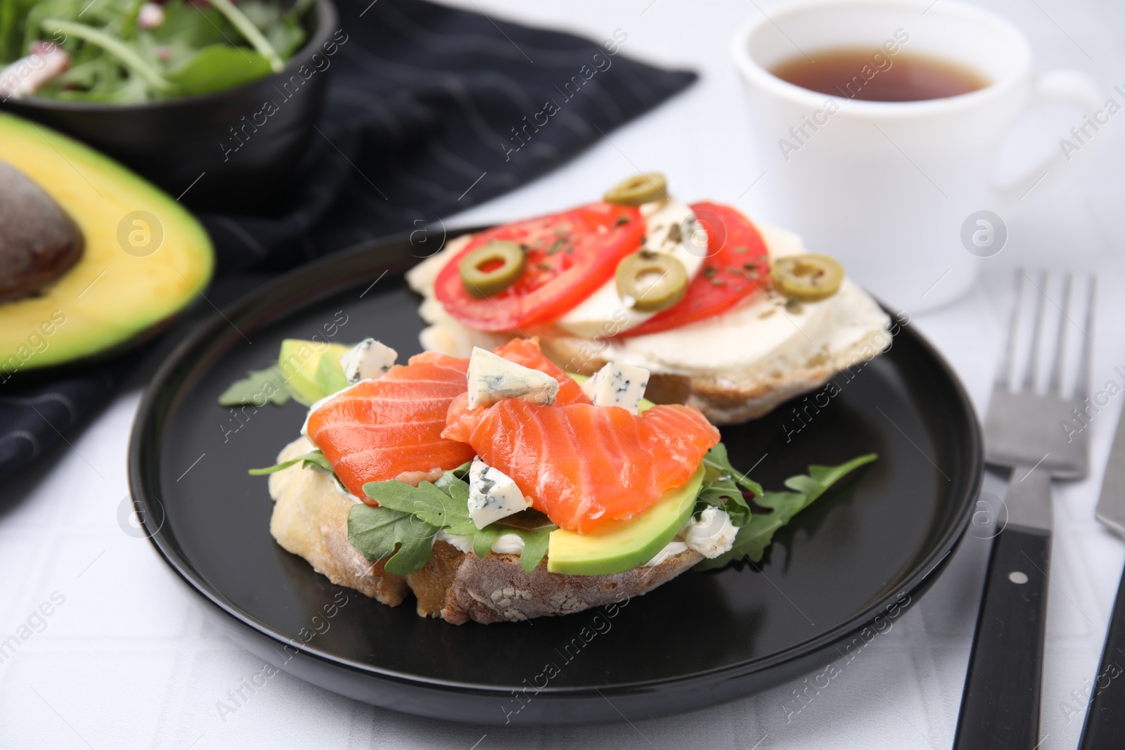 Photo of Different tasty bruschettas served on white tiled table, closeup