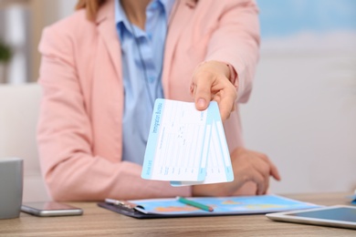 Photo of Female consultant holding tickets in travel agency, closeup