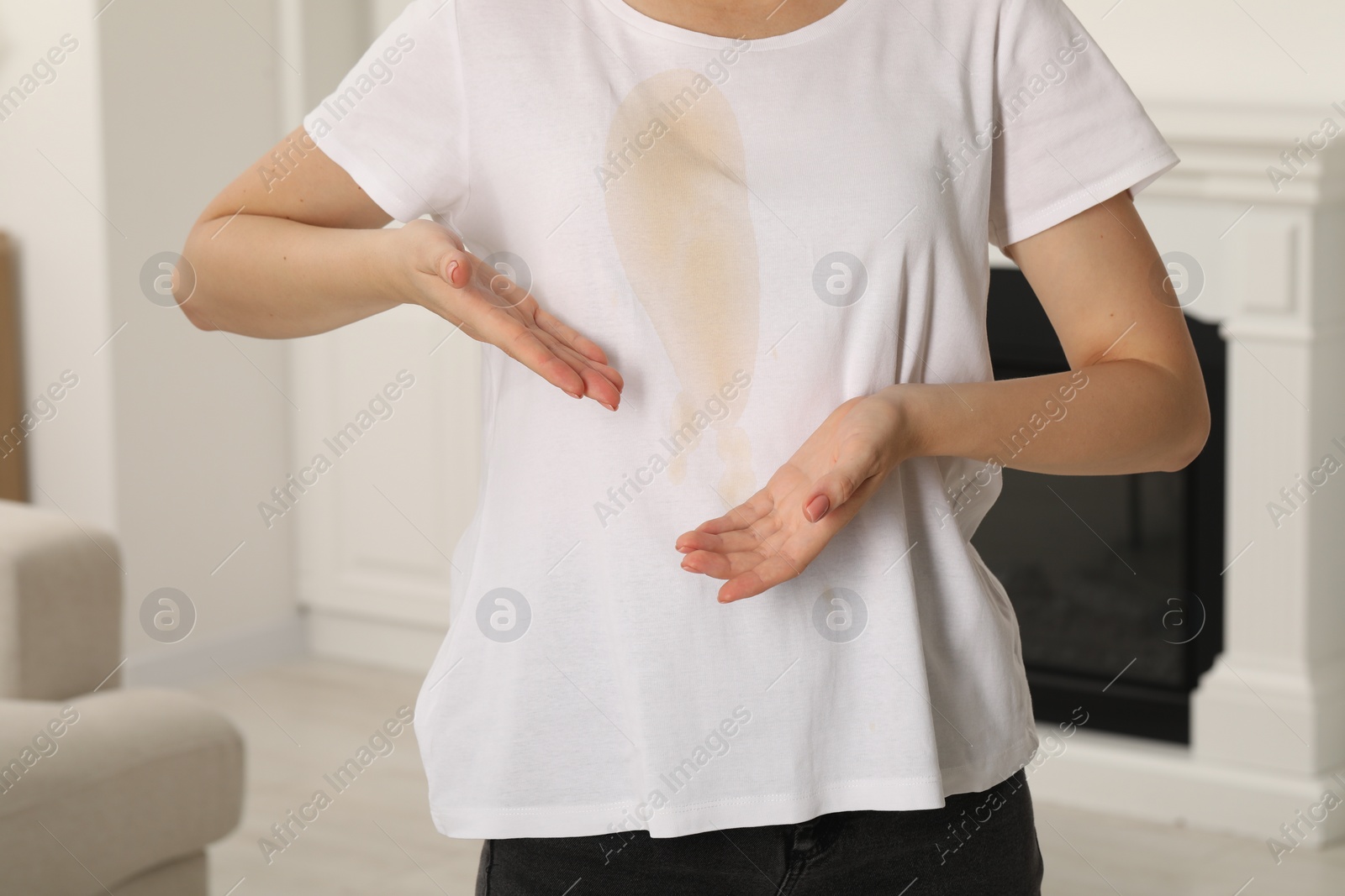 Photo of Woman showing stain from coffee on her shirt indoors, closeup