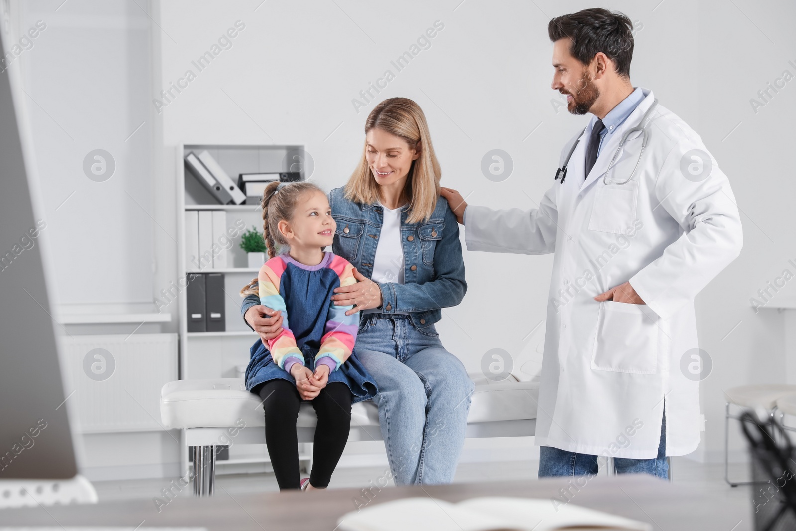 Photo of Happy mother and daughter having appointment with doctor. Pediatrician consulting patient in clinic