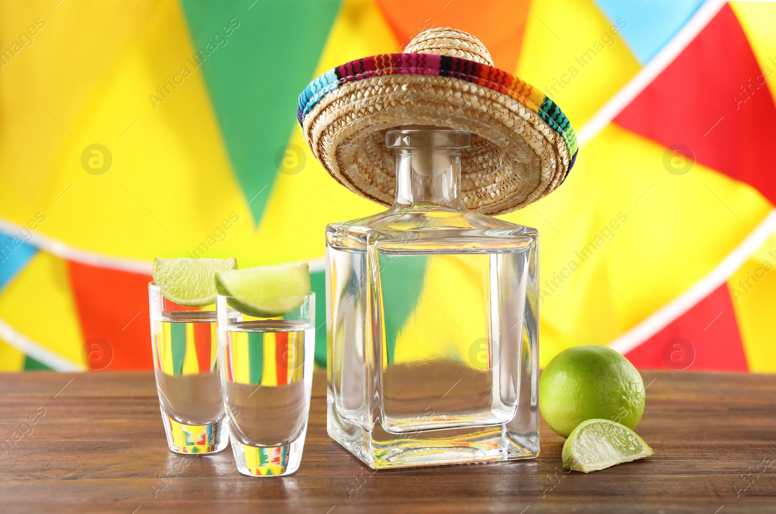 Photo of Mexican sombrero hat, tequila and lime on wooden table