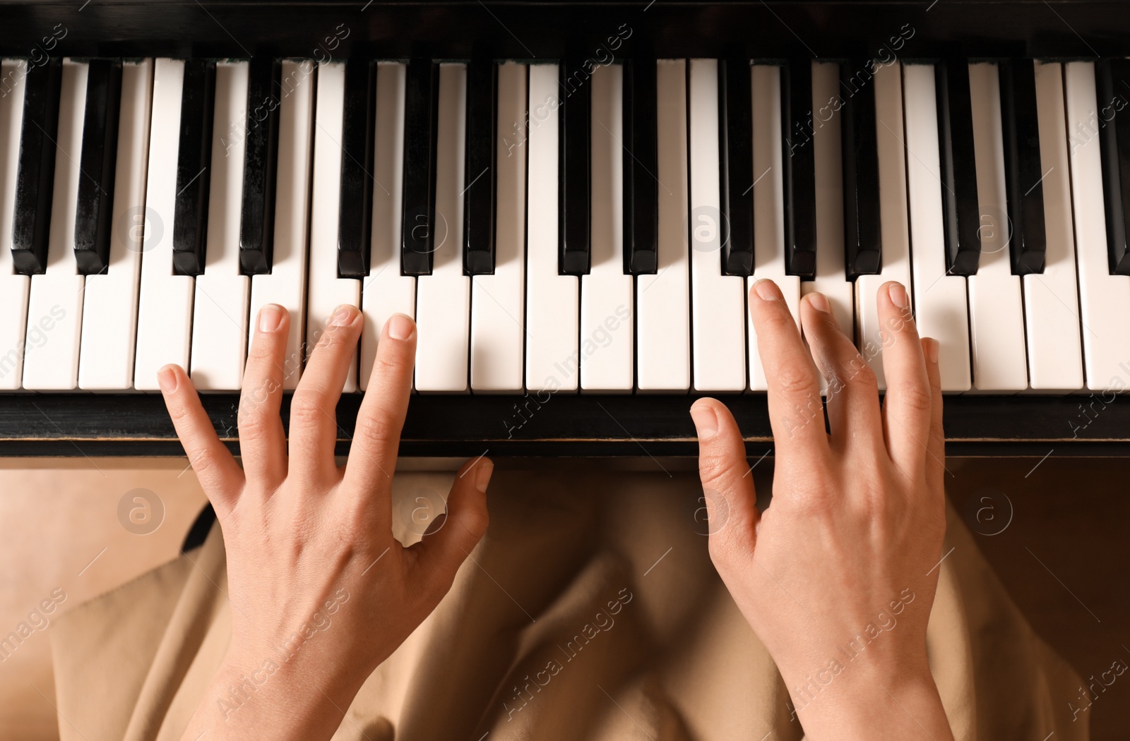 Photo of Young woman playing piano, above view. Music lesson