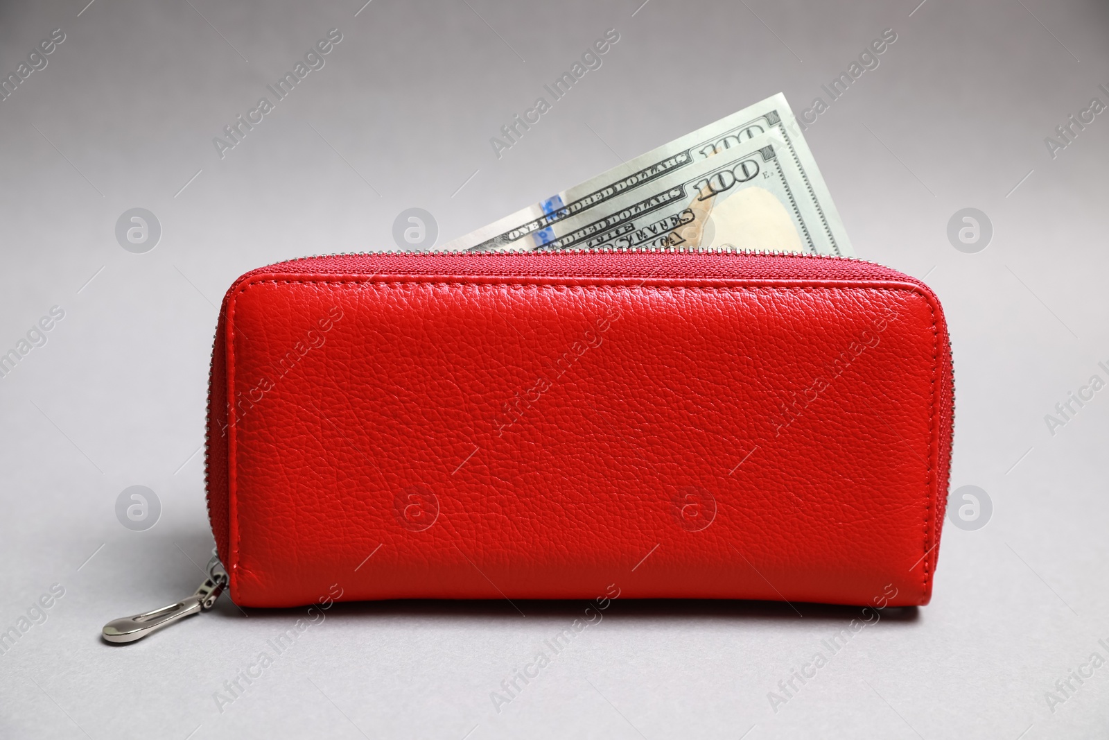 Photo of Stylish red leather purse with dollar banknotes on light grey background