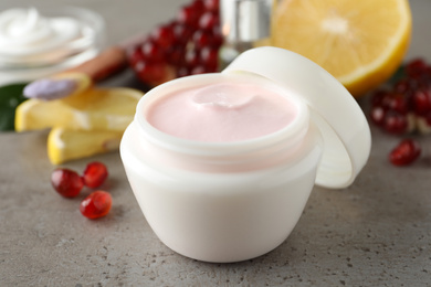 Photo of Natural facial mask and pomegranate seeds on light grey table, closeup