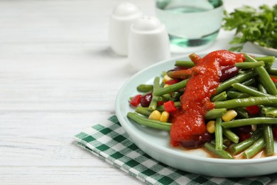 Photo of Delicious salad with green beans and tomato sauce served on white wooden table, closeup. Space for text