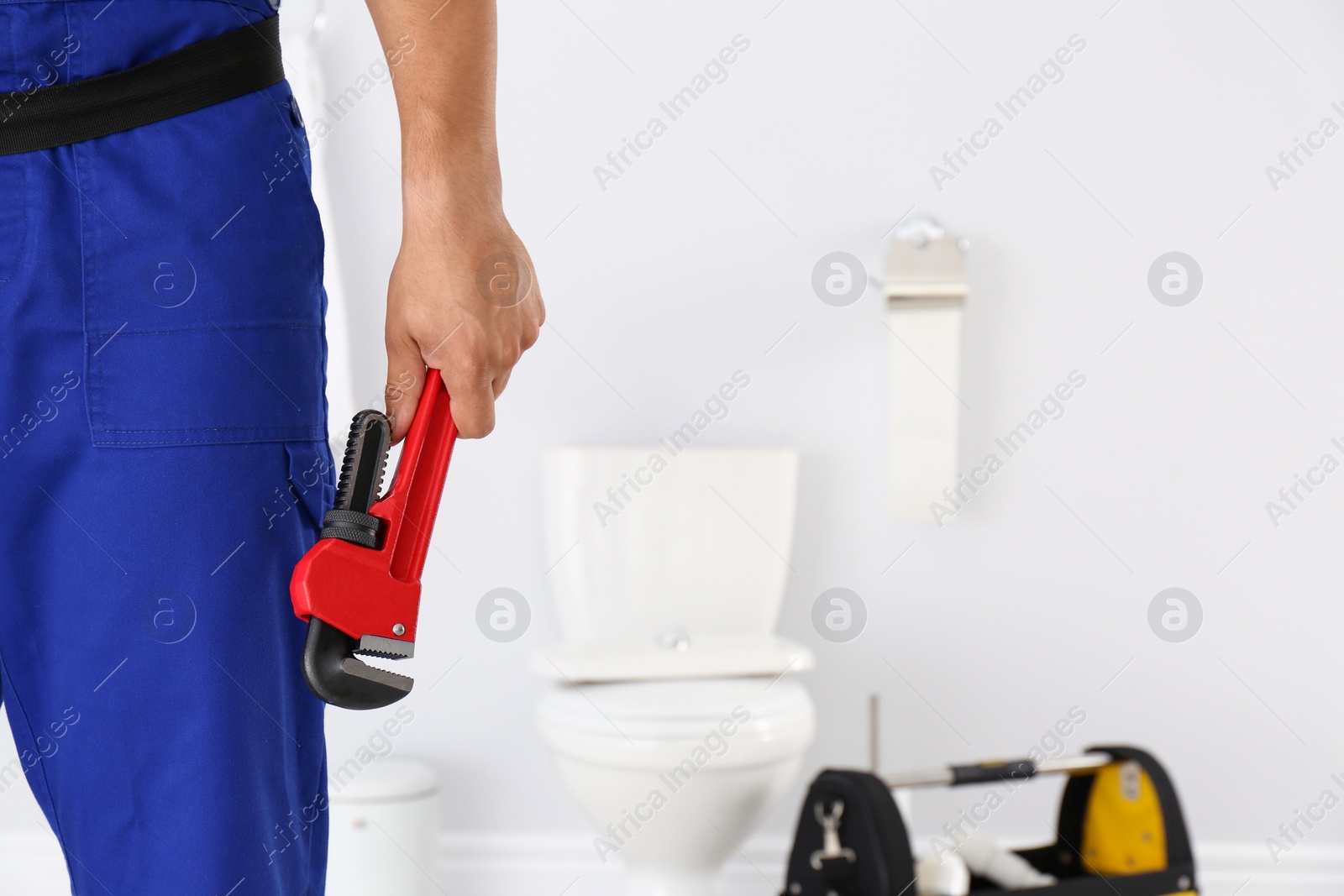 Photo of Young man with plumber wrench and toilet bowl on background