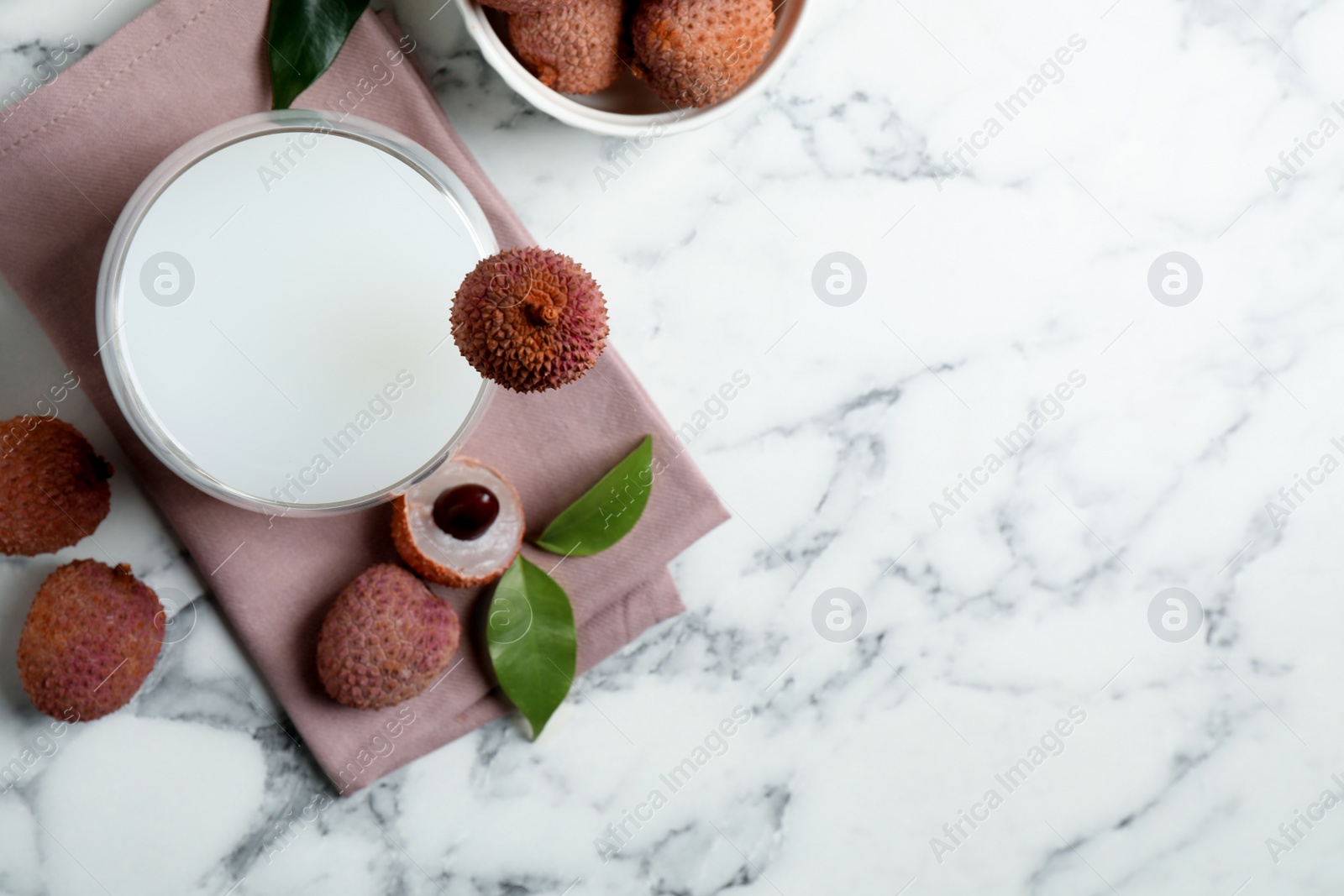 Photo of Fresh lychee juice and fruits on white marble table, flat lay. Space for text