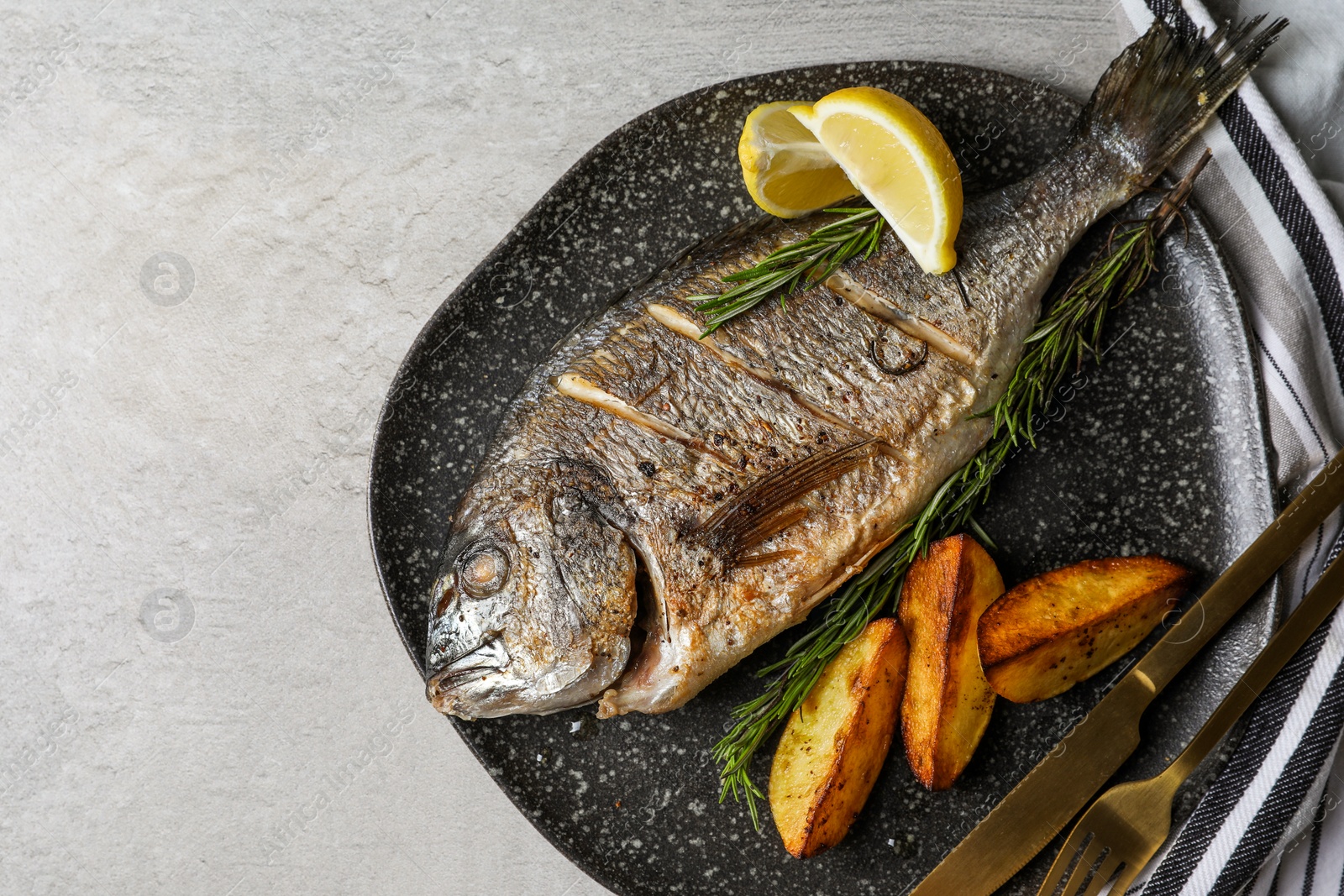 Photo of Seafood. Delicious baked fish served on grey table, top view with space for text