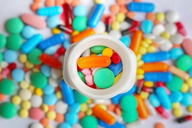 Bottle and many colorful pills, top view