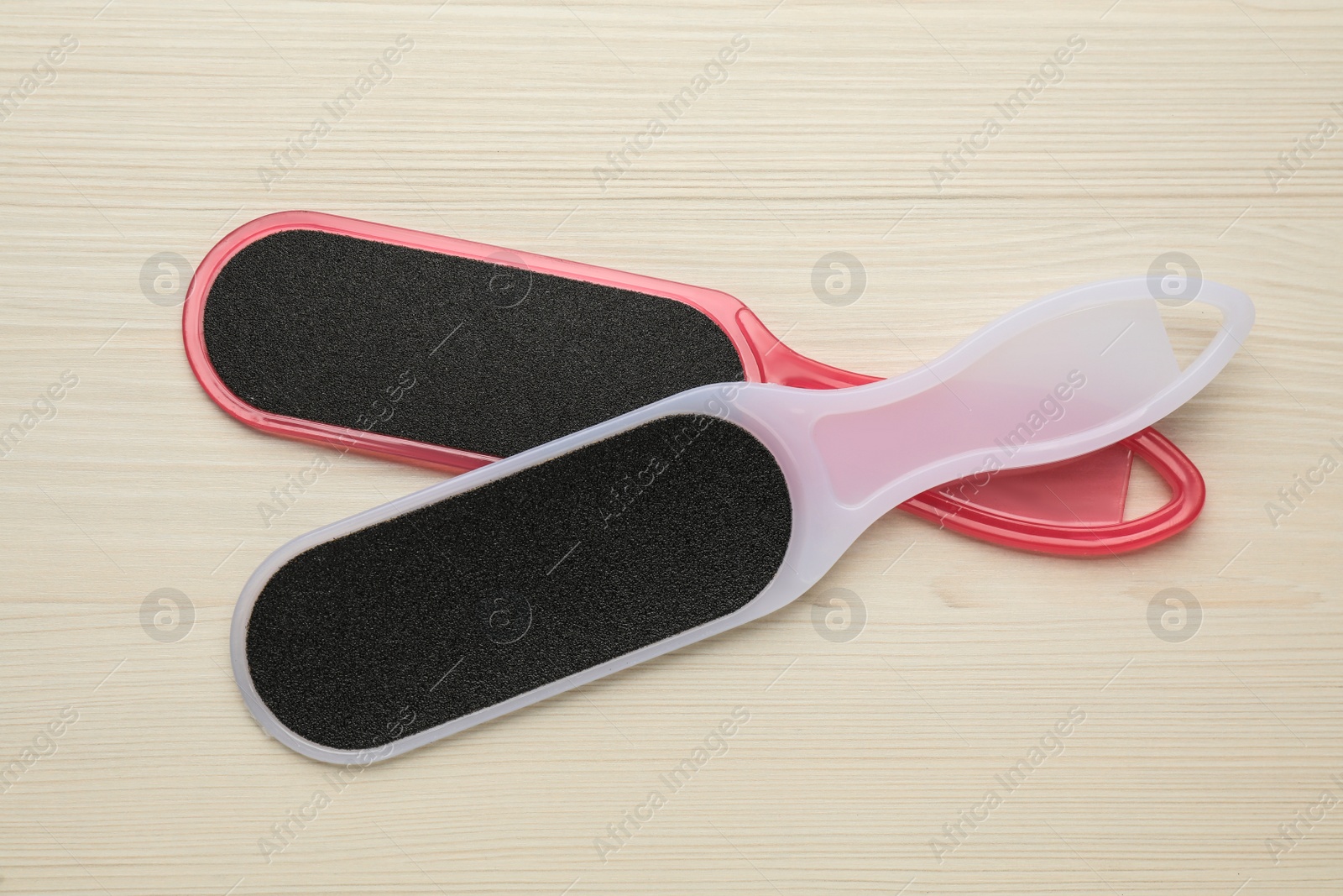 Photo of Colorful foot files on white wooden table, flat lay. Pedicure tools