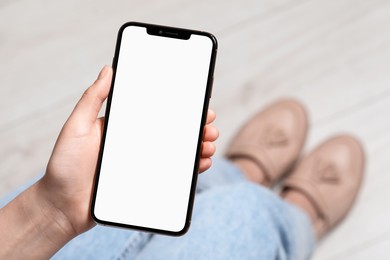 Photo of Woman holding smartphone with blank screen indoors, top view. Mockup for design